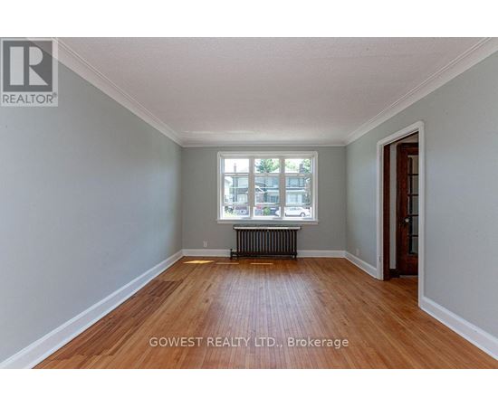 A room with wooden floors and a window with a view of a street.