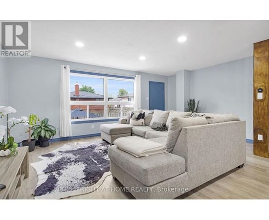 A living room with a grey couch and a large window.