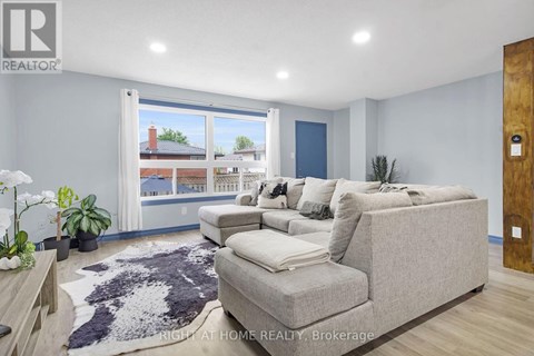 A living room with a grey couch and a large window.