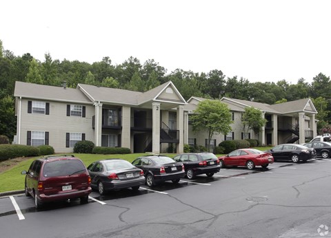 A parking lot with cars and apartment buildings in the background.
