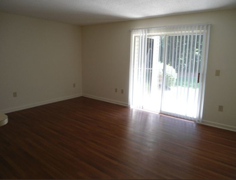 A room with wooden floors and a sliding glass door.