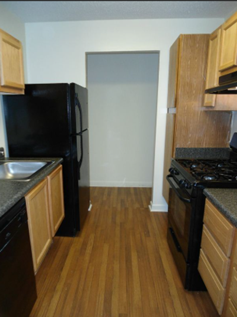 A kitchen with black appliances and wooden cabinets.