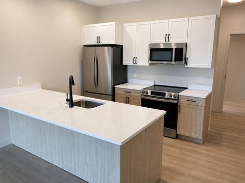 A kitchen with a white counter top and stainless steel appliances.