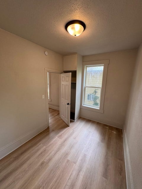 A room with a wooden floor and a window with a view of a building outside.
