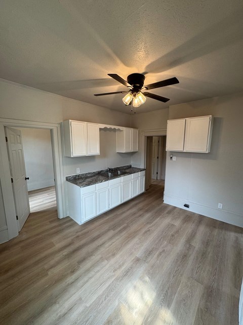 A room with a ceiling fan and wooden flooring.