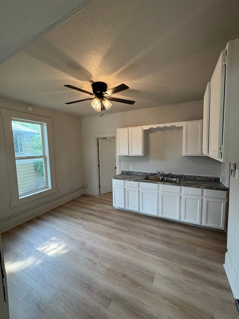 A kitchen with white cabinets and a ceiling fan.