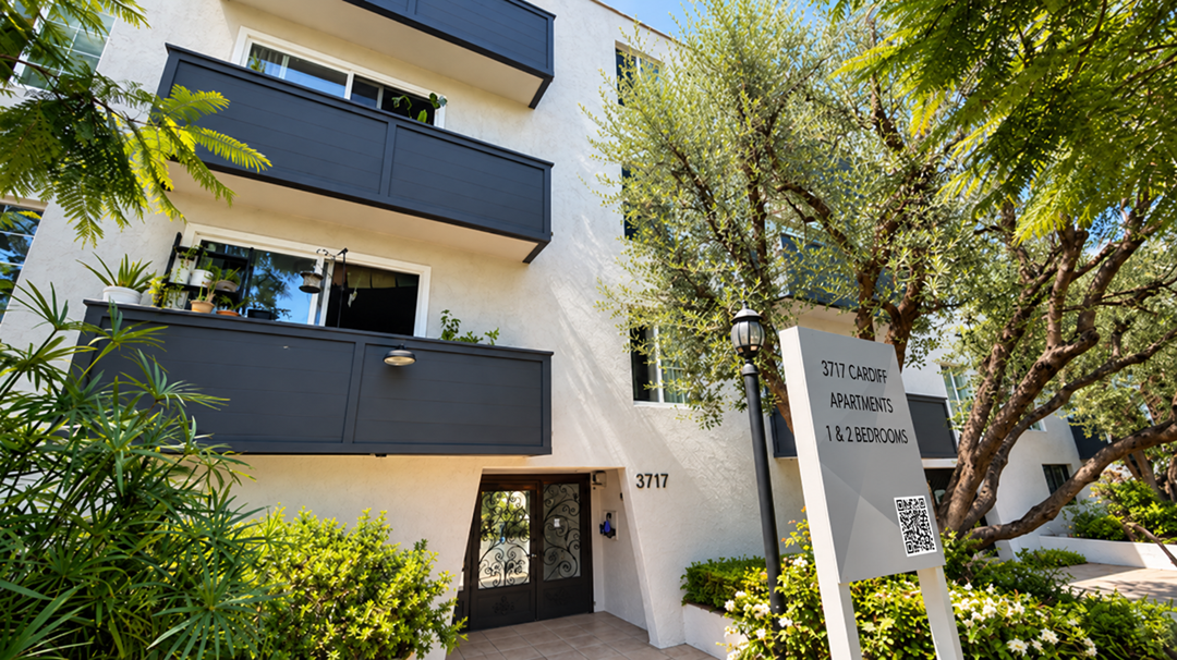 A modern apartment building with a sign in front that reads "STI CADOR APARTMENTS 1-28 BEDROOM".