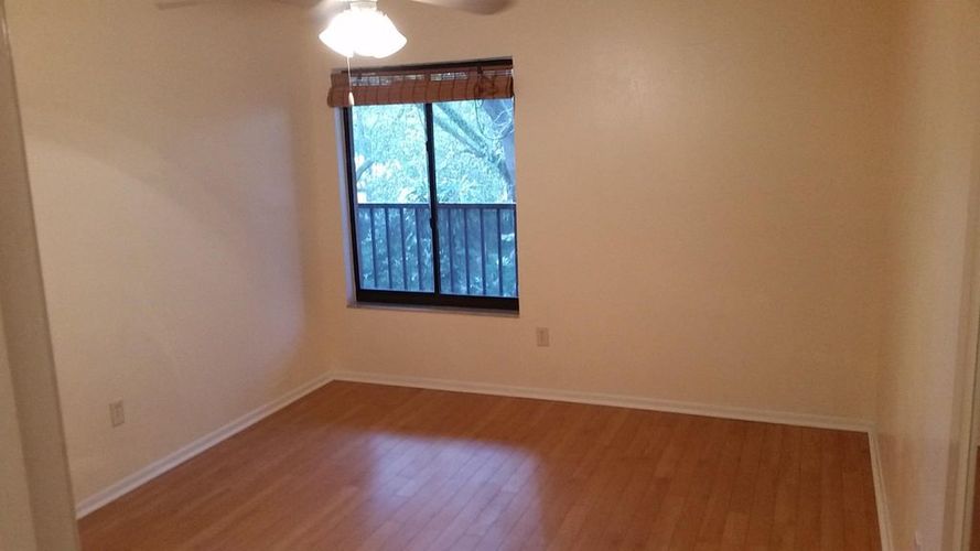 A room with wooden floors and a window with blinds.