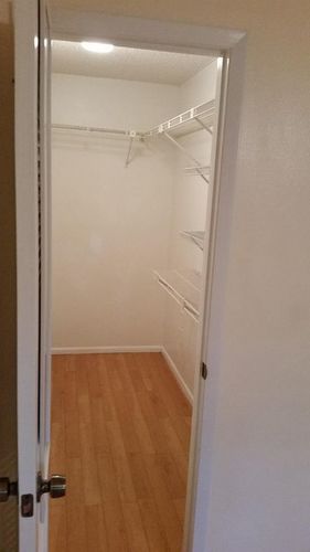 A white door is open to a room with a wooden floor.