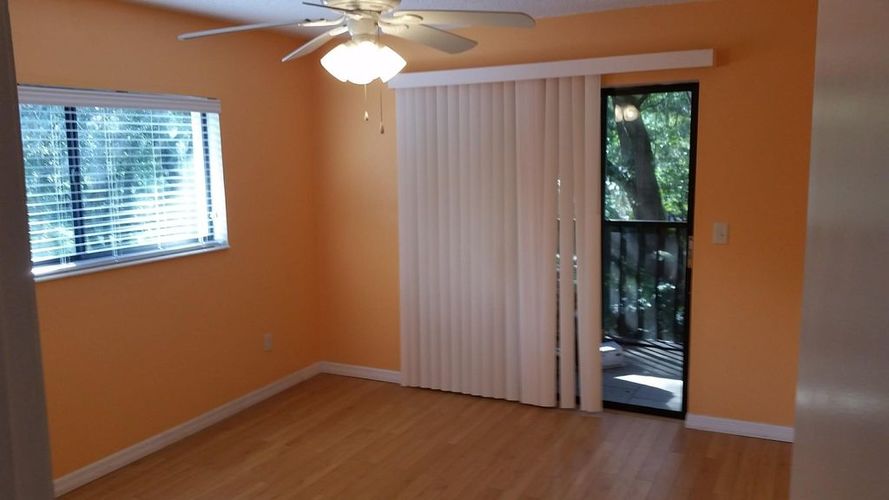 A room with a ceiling fan and a window with blinds.