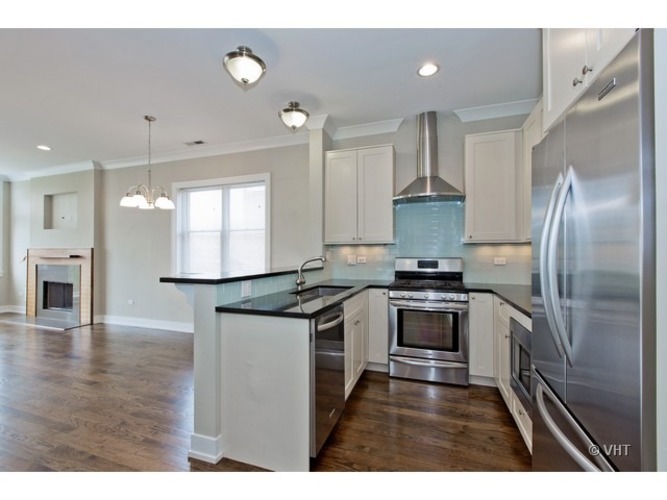 A modern kitchen with a stainless steel refrigerator and a black countertop.