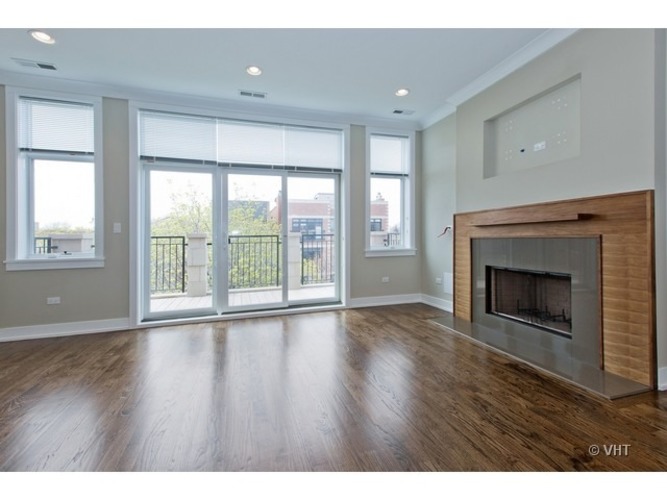 A large, empty room with a fireplace and sliding glass doors.