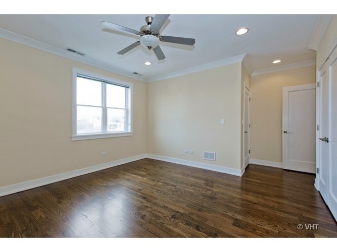 A room with a ceiling fan and wooden flooring.