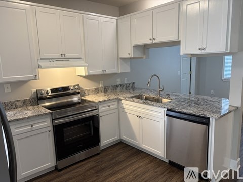 A kitchen with white cabinets and a granite countertop.