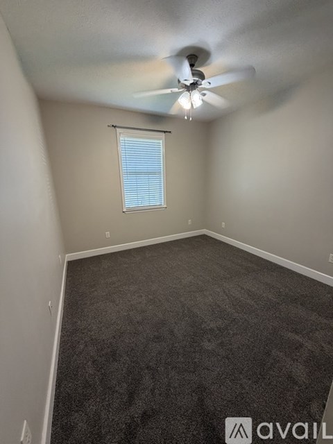 A room with a ceiling fan and carpeted floor.
