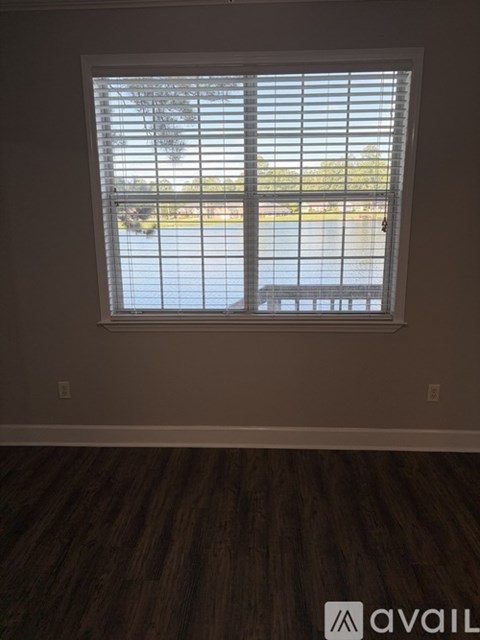 A window with blinds overlooking a parking lot.