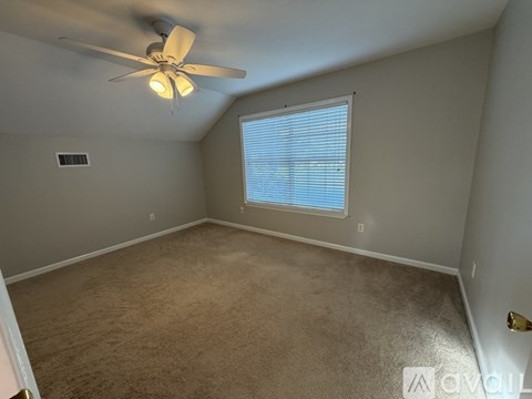 A room with a ceiling fan and a window with blinds.