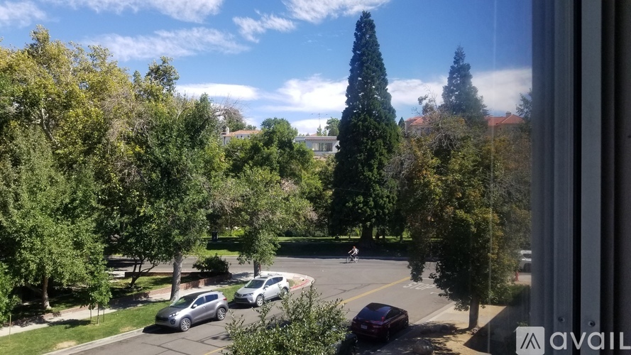 A view from a window looking out at a street with cars and trees.
