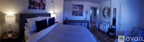 A bedroom with a large bed and a painting on the wall.