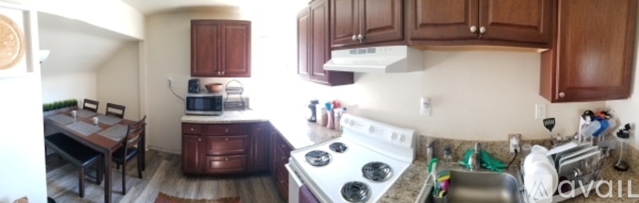 A kitchen with a stove top oven and a dining table with chairs.