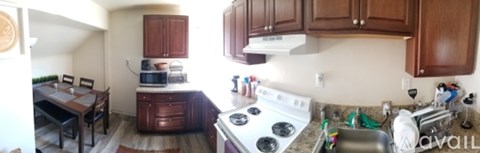 A kitchen with a stove top oven and a dining table with chairs.