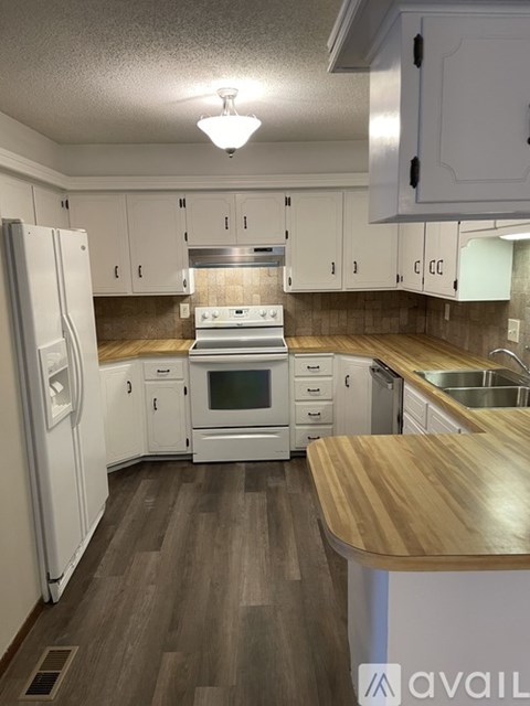 A kitchen with white cabinets and a wooden counter.