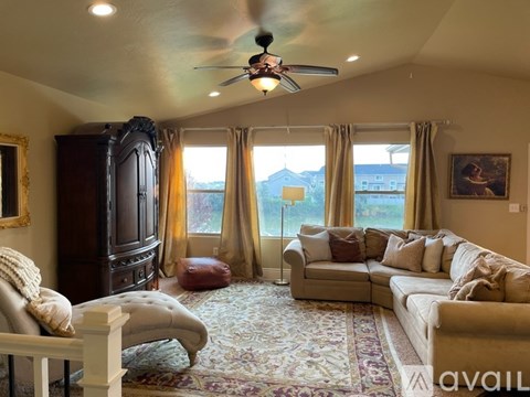 A living room with a large window, a couch, a chair, and a rug.