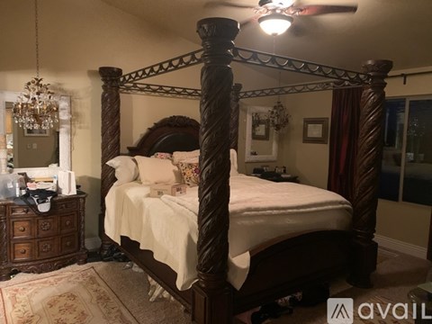 A bedroom with a four poster bed and a chandelier.