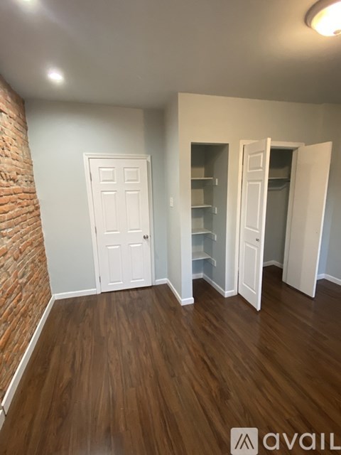 A room with a wooden floor and a brick wall.