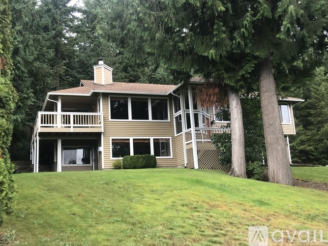 A house with a balcony and a tree in front of it.