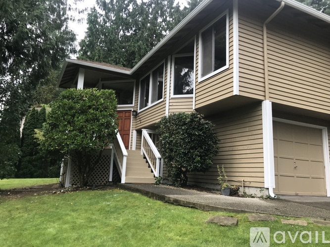 A house with a brown siding and a white garage door is for sale.