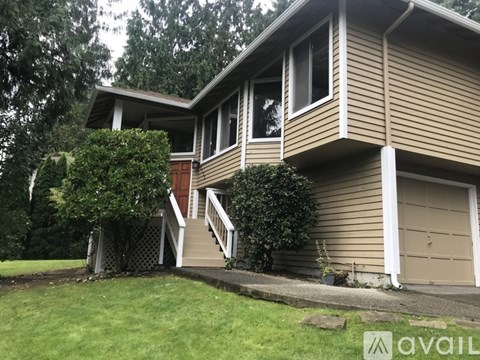A house with a brown siding and a white garage door is for sale.