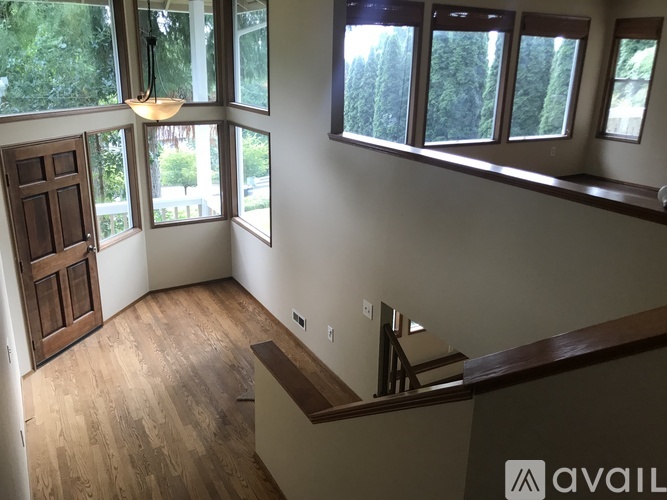 A room with a wooden floor and a large window overlooking trees.