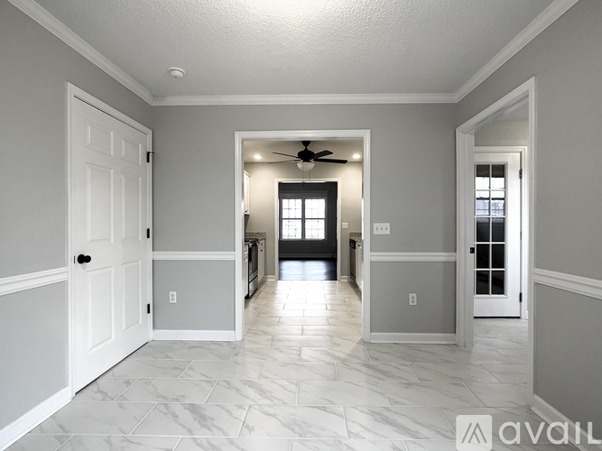 A spacious hallway with a fan and a door on the left.