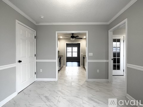 A spacious hallway with a fan and a door on the left.