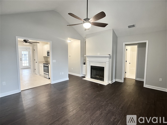 A spacious living room with a fireplace and a ceiling fan.