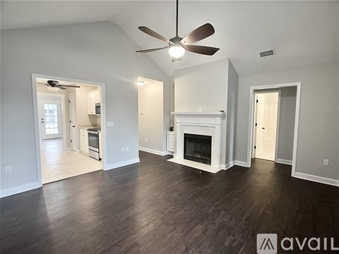 A spacious living room with a fireplace and a ceiling fan.