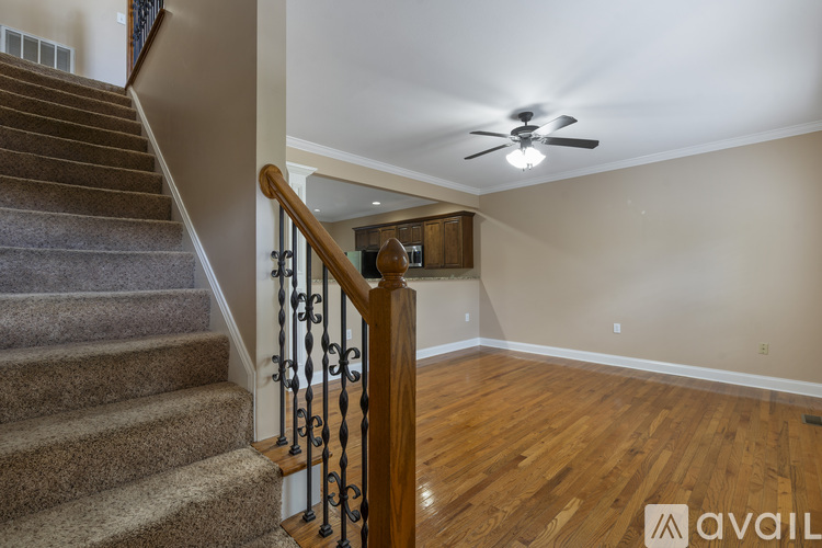 A staircase with a wooden banister and a fan in the room.