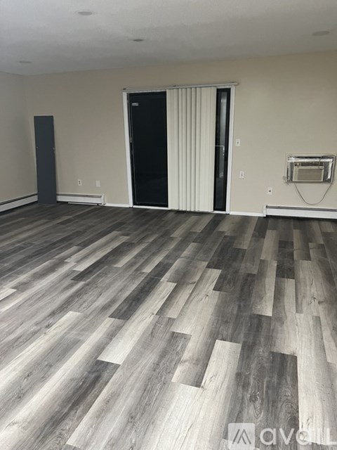 A room with wooden flooring and a black door.
