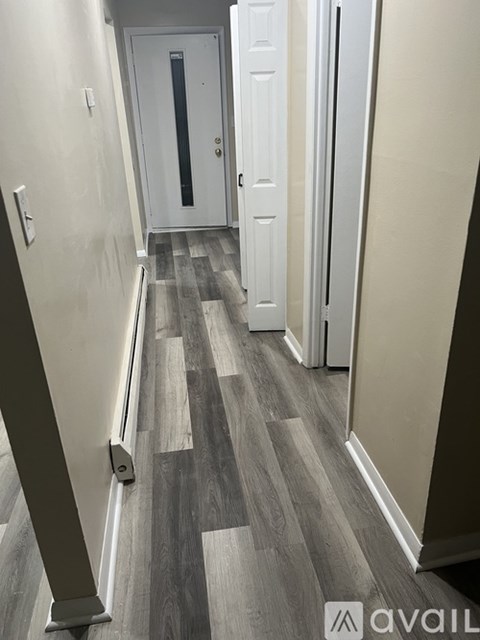 A hallway with a wooden floor and white walls.