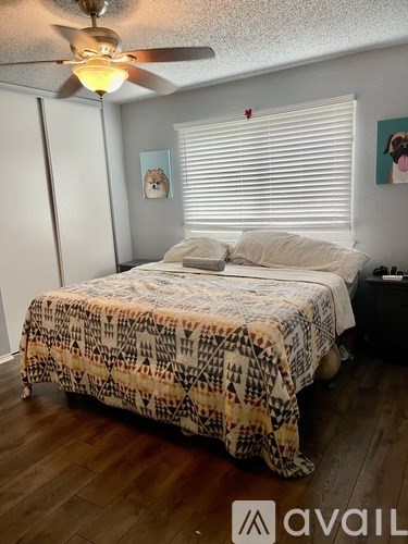 A bedroom with a bed covered in a patterned bedspread and a ceiling fan above.