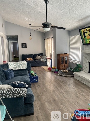 A living room with a dark blue couch and a fan on the ceiling.