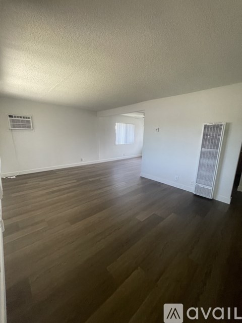 A room with wooden flooring and white walls.