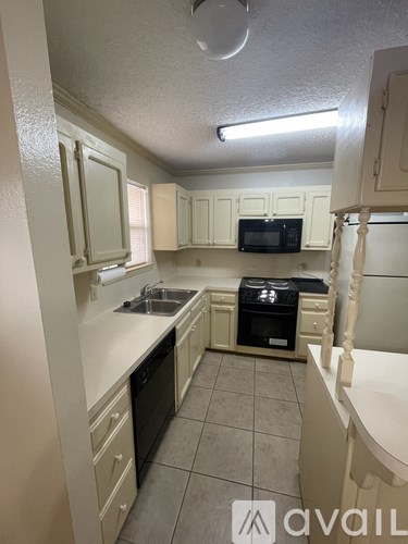A kitchen with white cabinets and black appliances.