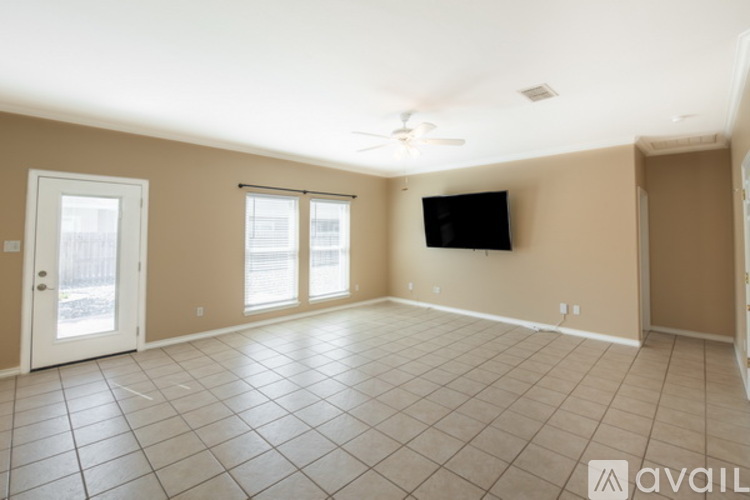 A spacious room with a flat screen TV mounted on the wall and a sliding glass door.