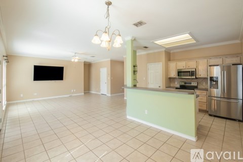 A spacious kitchen and living room with a television and a chandelier.