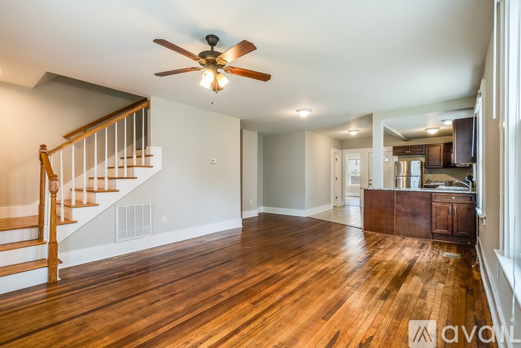 A spacious room with wooden floors and a ceiling fan.