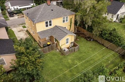 A house with a yellow exterior is surrounded by a fence and greenery.