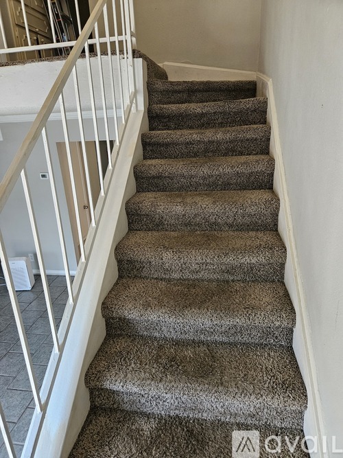 A staircase with a carpeted runner and white railings.