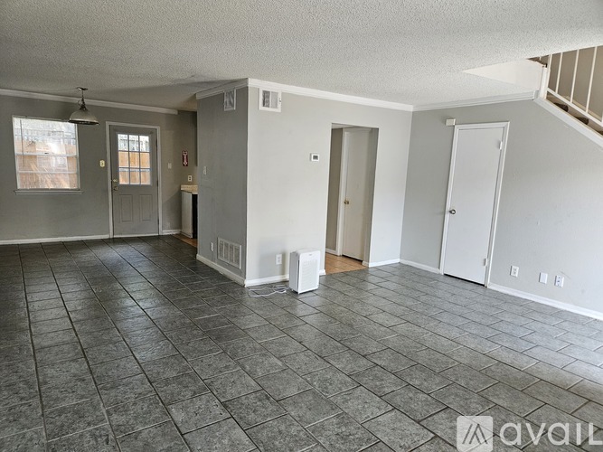 A spacious room with tile flooring and white walls.